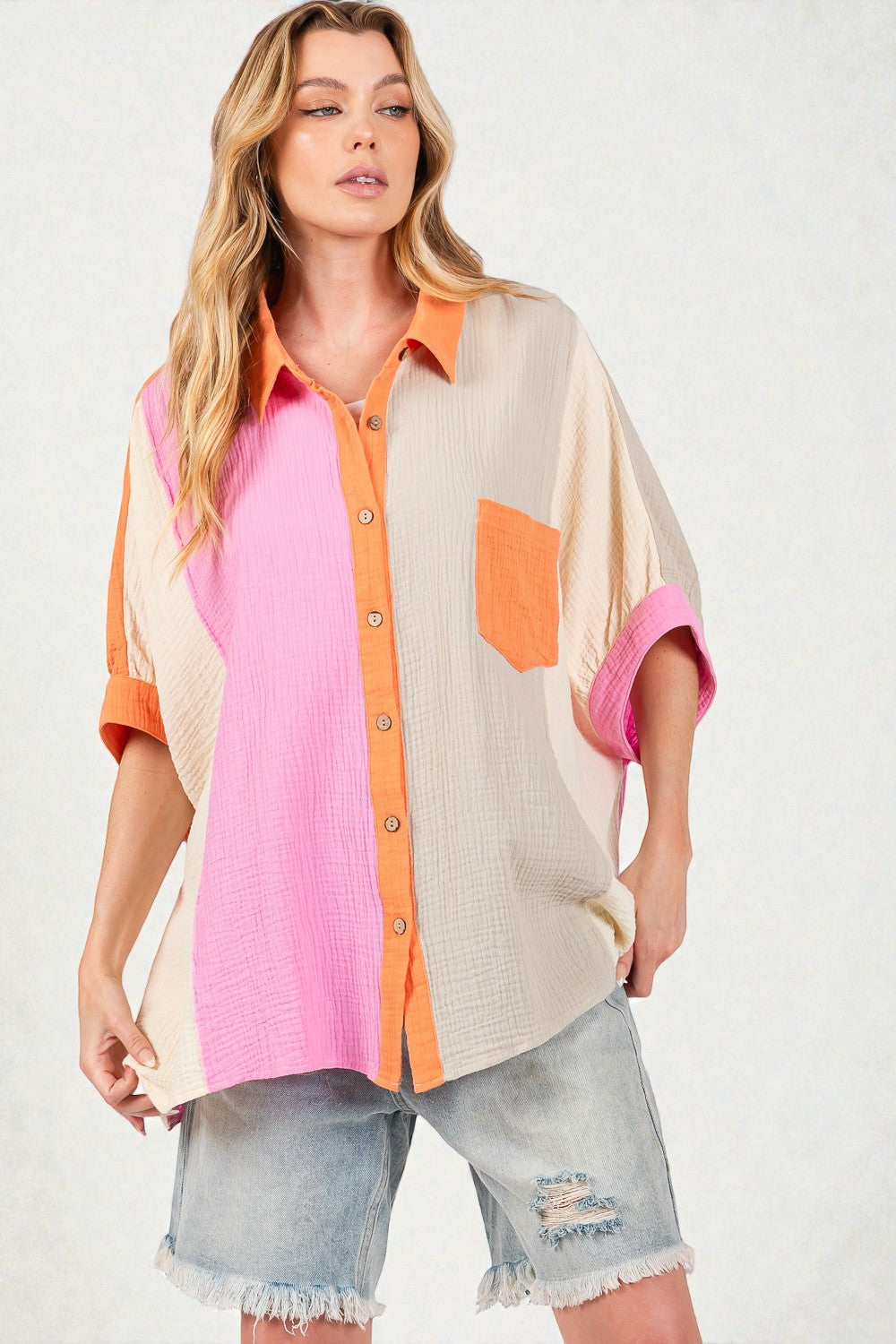 Woman wearing a colorful button-up shirt with pink, orange, and beige panels on a white background.