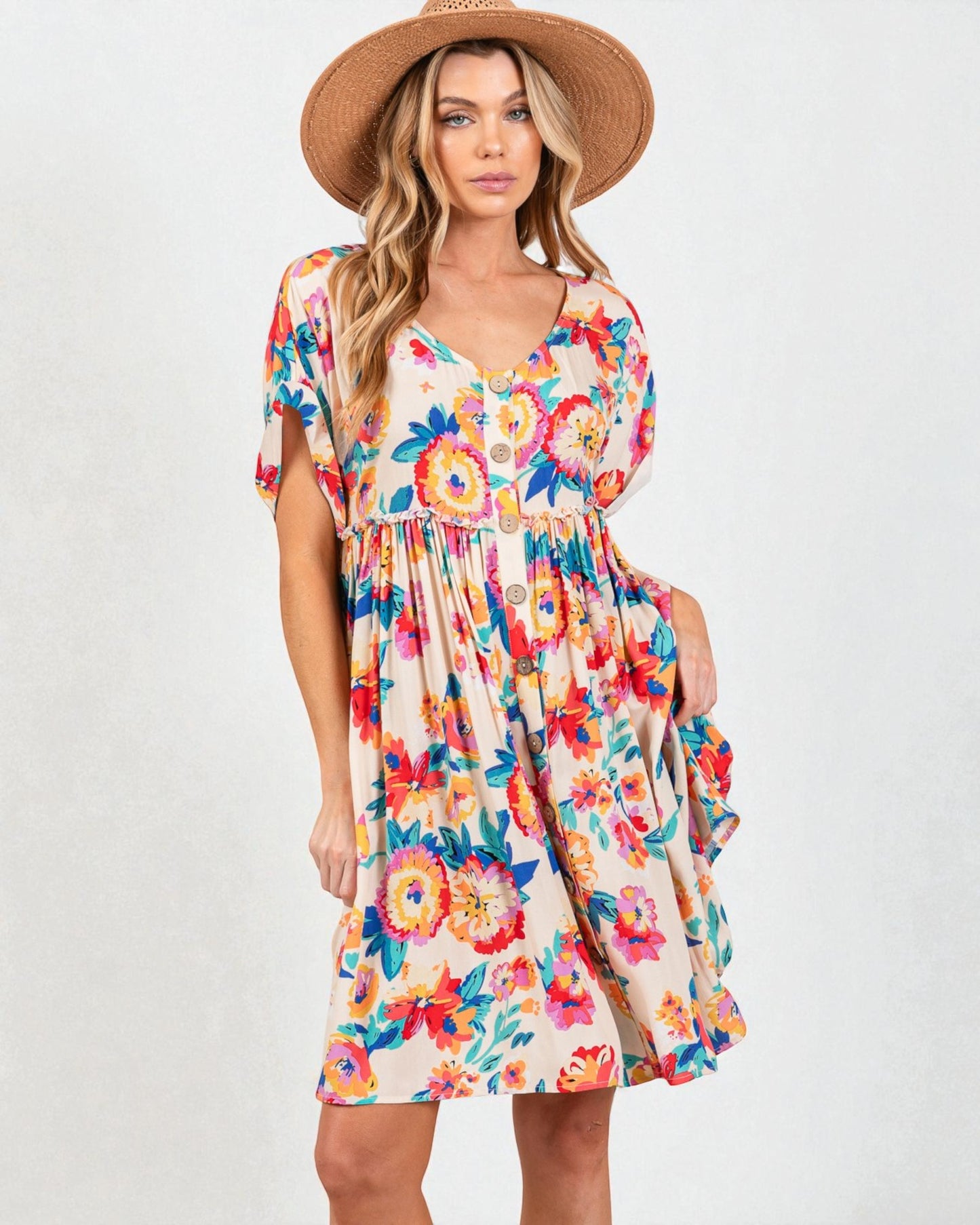 Woman wearing a colorful floral dress and straw hat on a white background