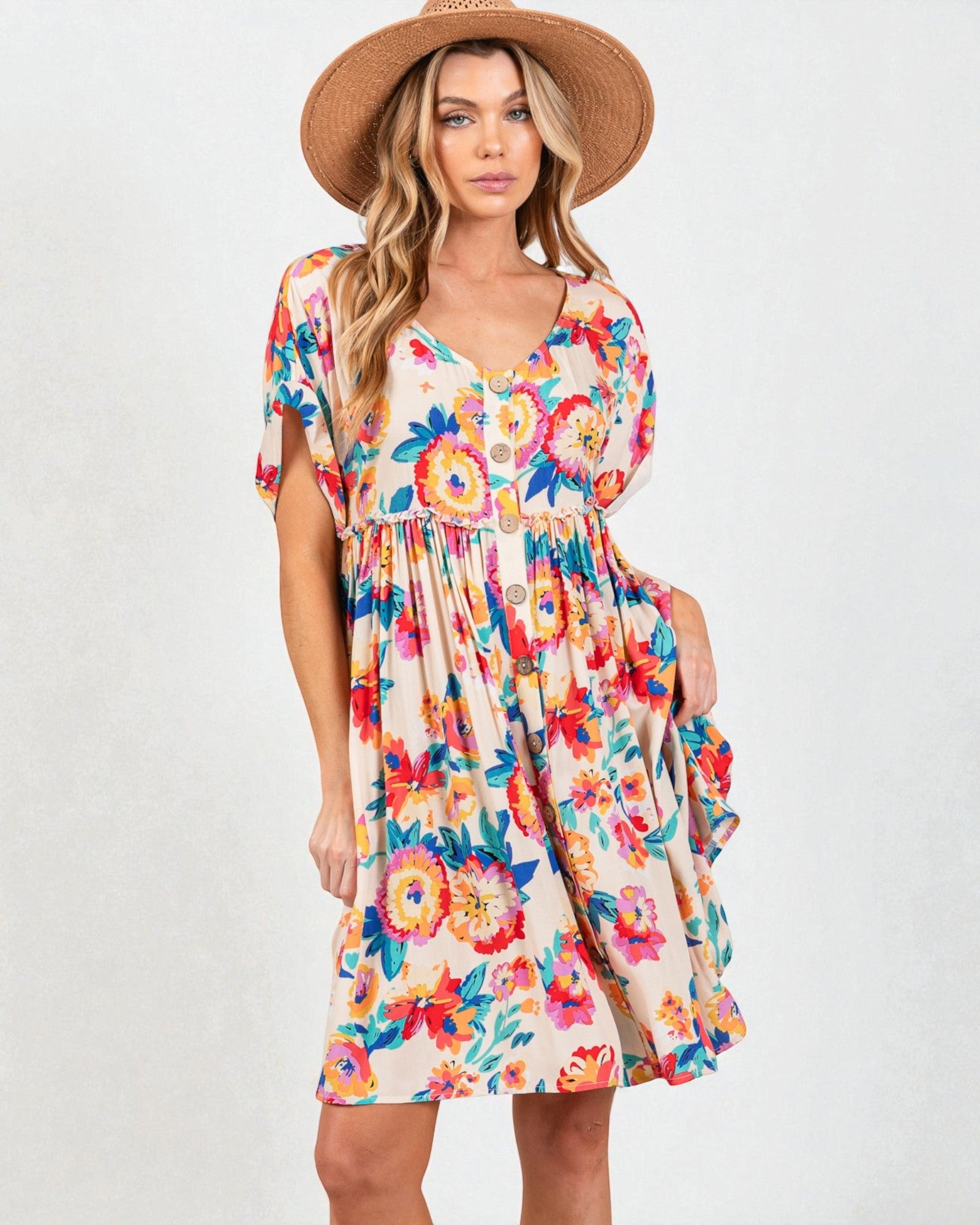 Woman wearing a colorful floral dress and straw hat on a white background