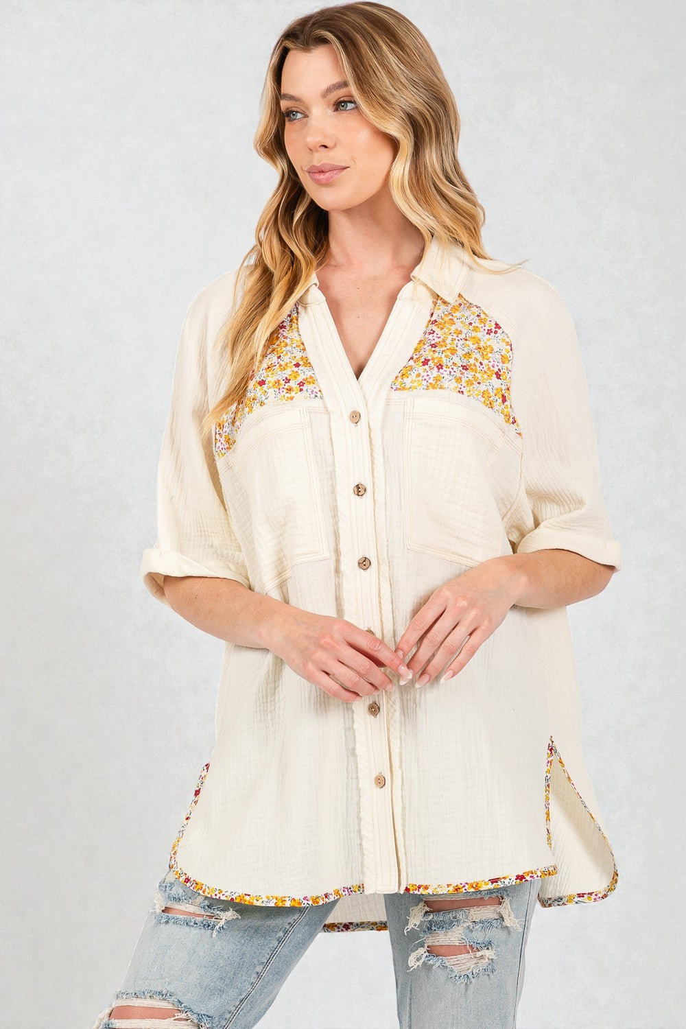 Woman wearing a cream-colored blouse with floral embroidery on a light gray background