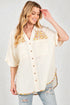 Woman wearing a cream-colored blouse with floral embroidery on a plain background