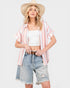 Woman wearing a striped kimono, white top, and denim shorts on a white background