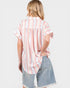 Woman wearing a striped shirt and denim shorts on a plain background