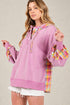 Woman wearing a pink hoodie with plaid sleeves on a beige background