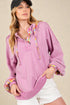 Woman wearing a pink hoodie with colorful trim on a beige background
