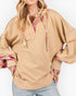 A woman wearing an oversized tan pullover hoodie with colorful tie-dye drawstrings and matching multicolor patterned inner cuffs, paired with light blue jeans against a plain white background.