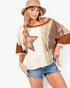 A woman modeling a bohemian-style patchwork top with a large star patch on the front, featuring cream, brown, and plaid patterns, paired with denim shorts and a tan hat against a white background.