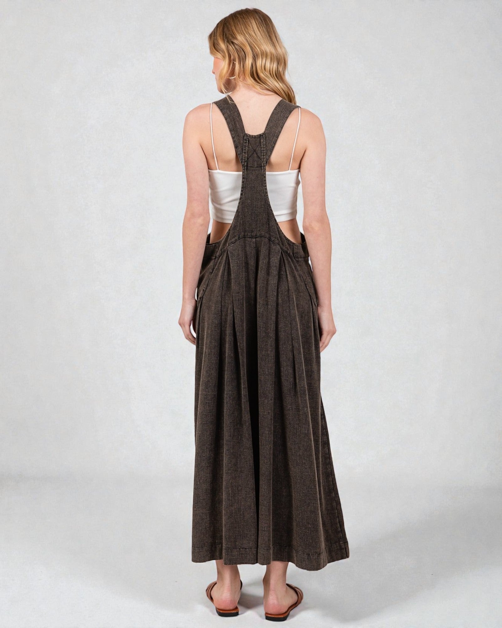 Woman wearing a long brown dress with cut-out sides on a white background