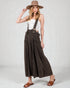 Woman wearing brown wide-leg pants with suspenders and a matching hat on a white background