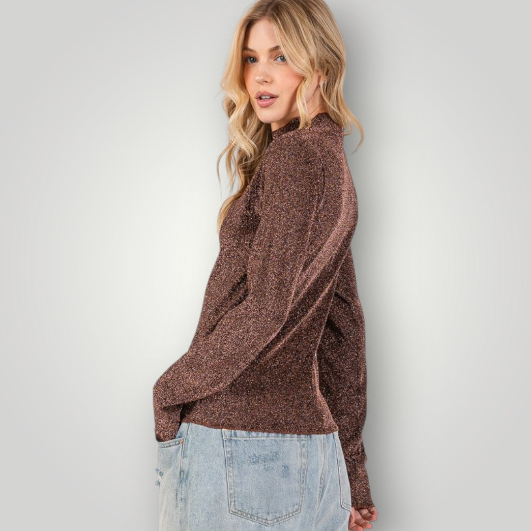 Woman wearing a brown sweater and light blue jeans against a plain background