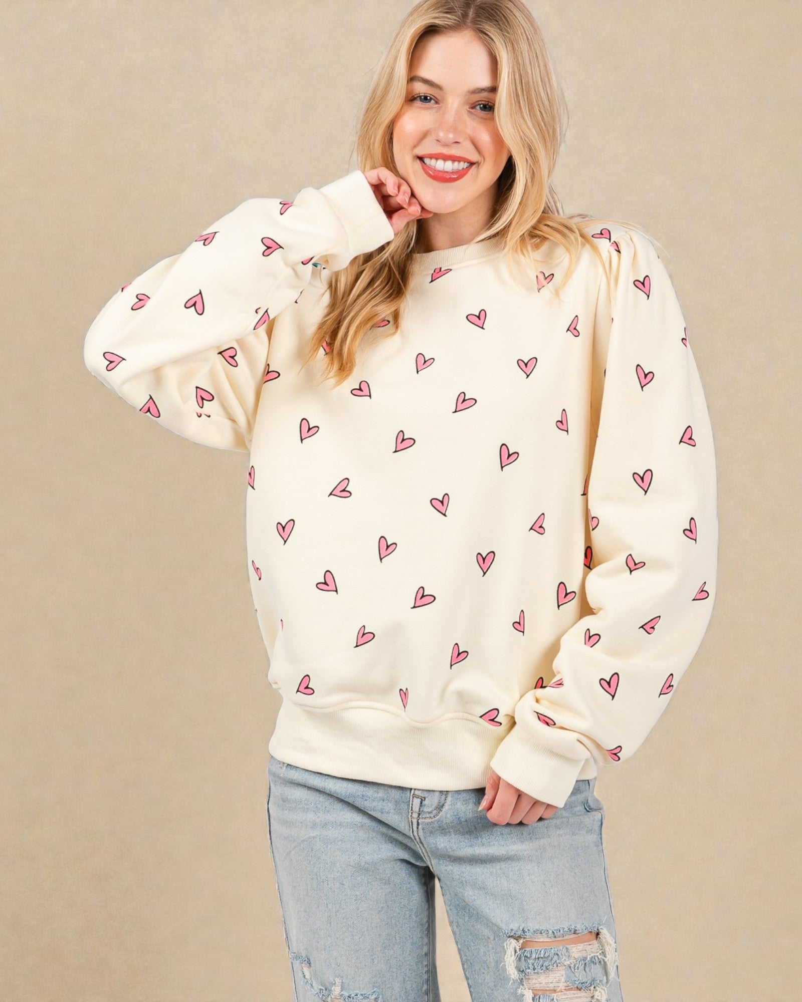 Woman wearing a cream sweatshirt with heart patterns on a beige background