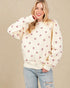 Woman wearing a cream sweatshirt with heart patterns on a beige background