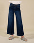 Person wearing dark blue wide-leg jeans on a beige background