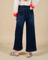 Person wearing dark blue wide-leg jeans on a beige background