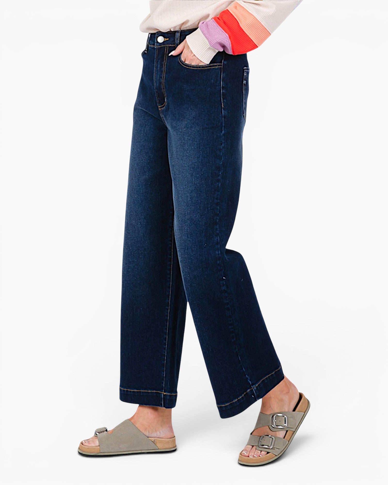 A person wearing dark blue wide-leg cropped jeans, styled with a cream top and colorful striped socks, paired with taupe double-strap slide sandals against a plain white background.