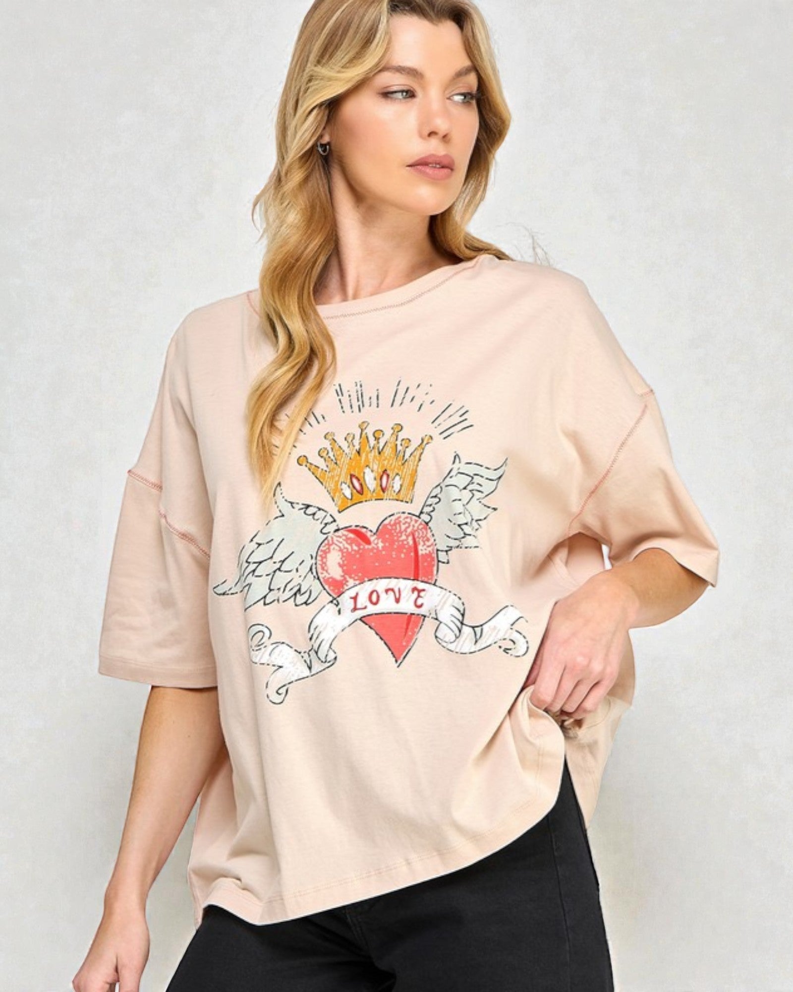 Woman wearing a beige t-shirt with a graphic design on a plain background