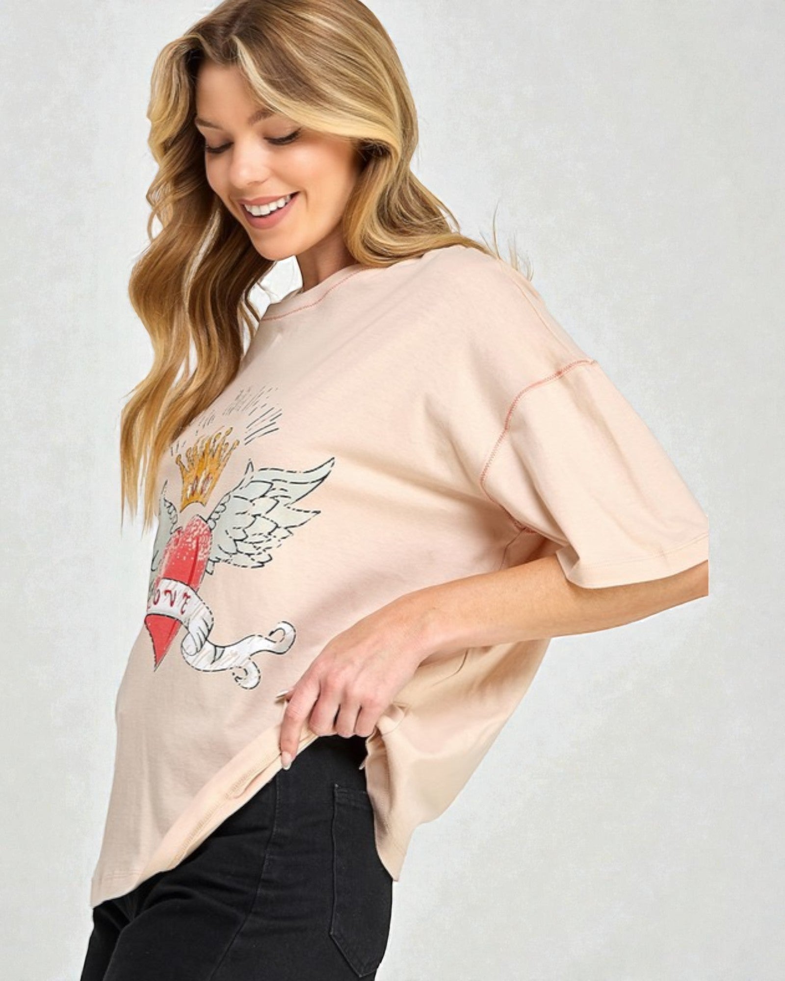 Woman wearing a beige t-shirt with a graphic design on a plain background