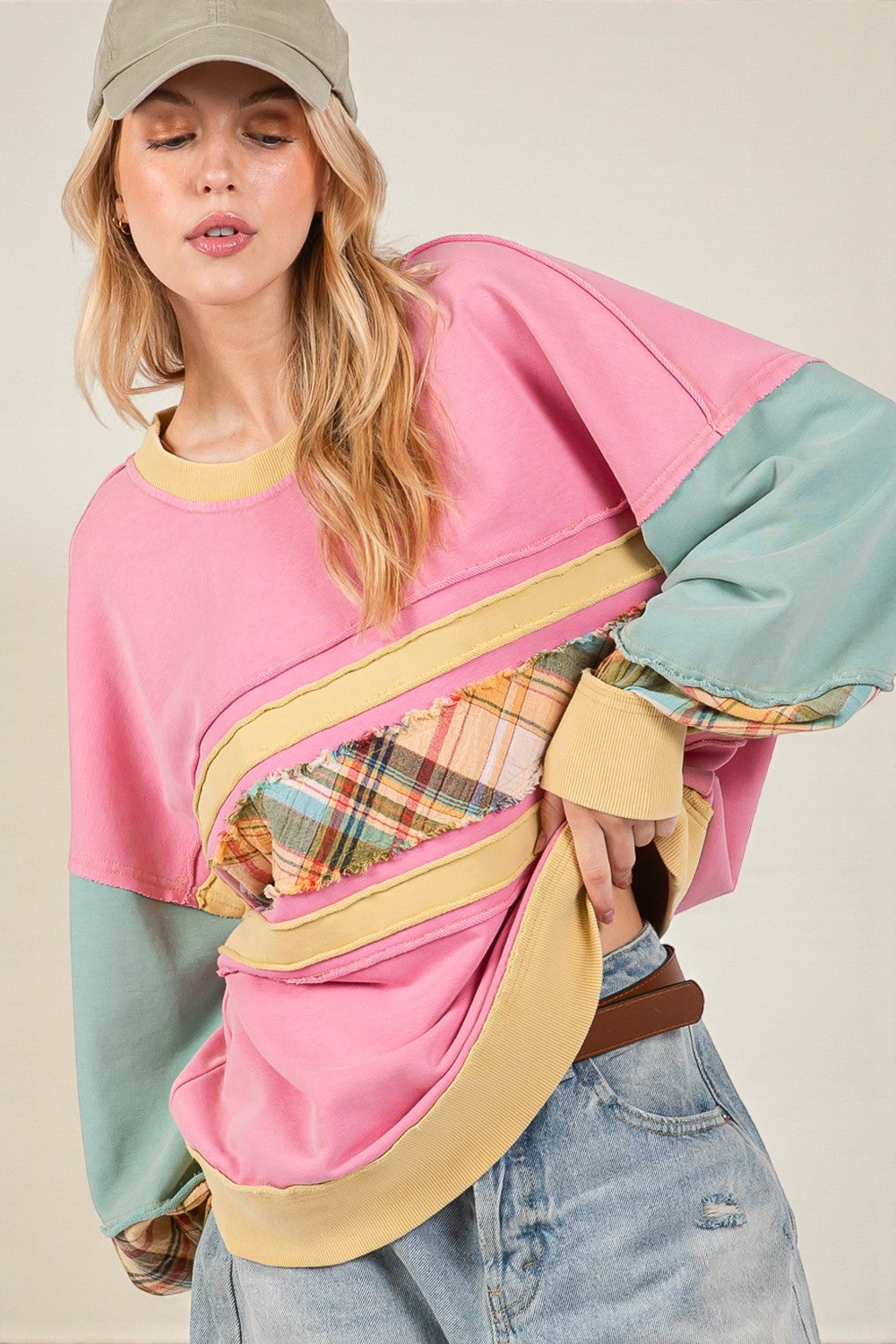 Woman wearing a colorful sweater with plaid accents against a neutral background