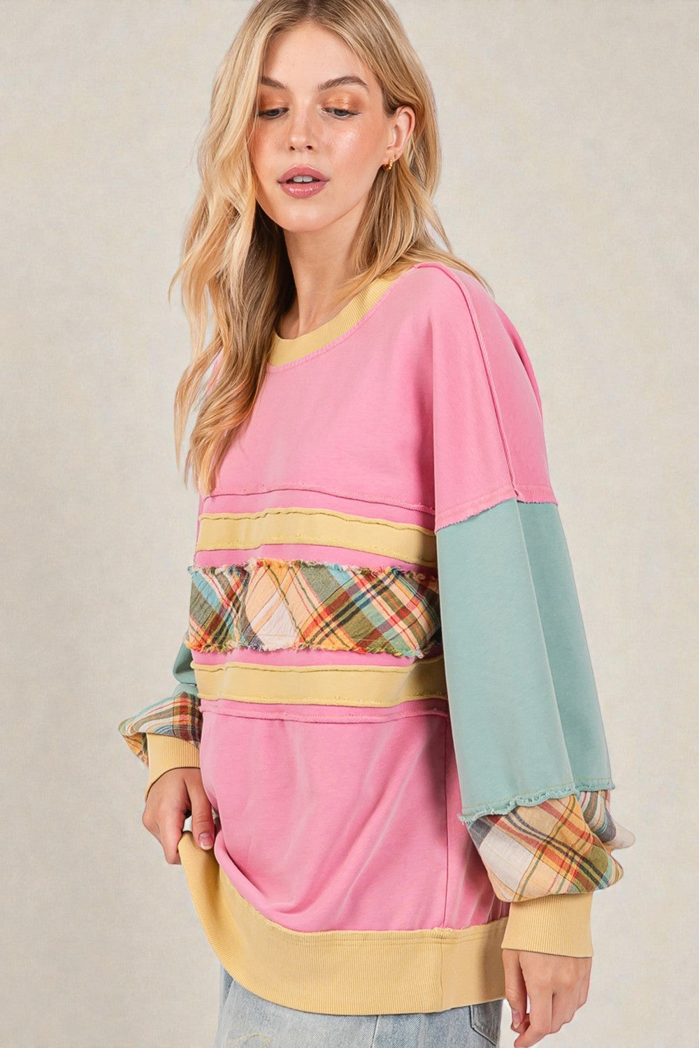 Woman wearing a colorful sweater with plaid pattern on a beige background