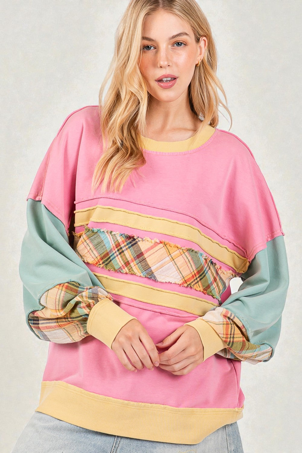 Woman wearing a colorful sweater with plaid sleeves on a white background