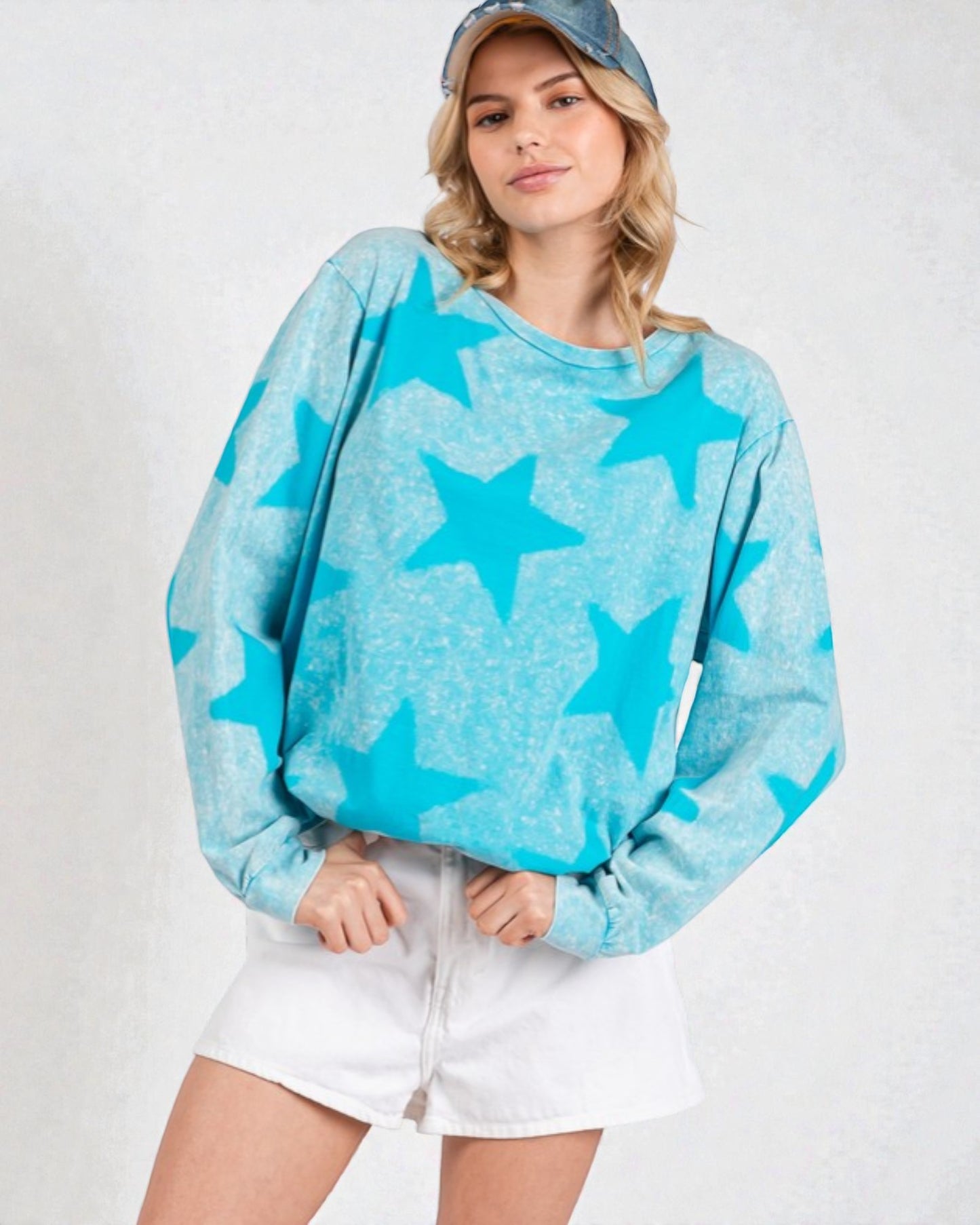 Person wearing a blue star-patterned sweater and white shorts on a plain background