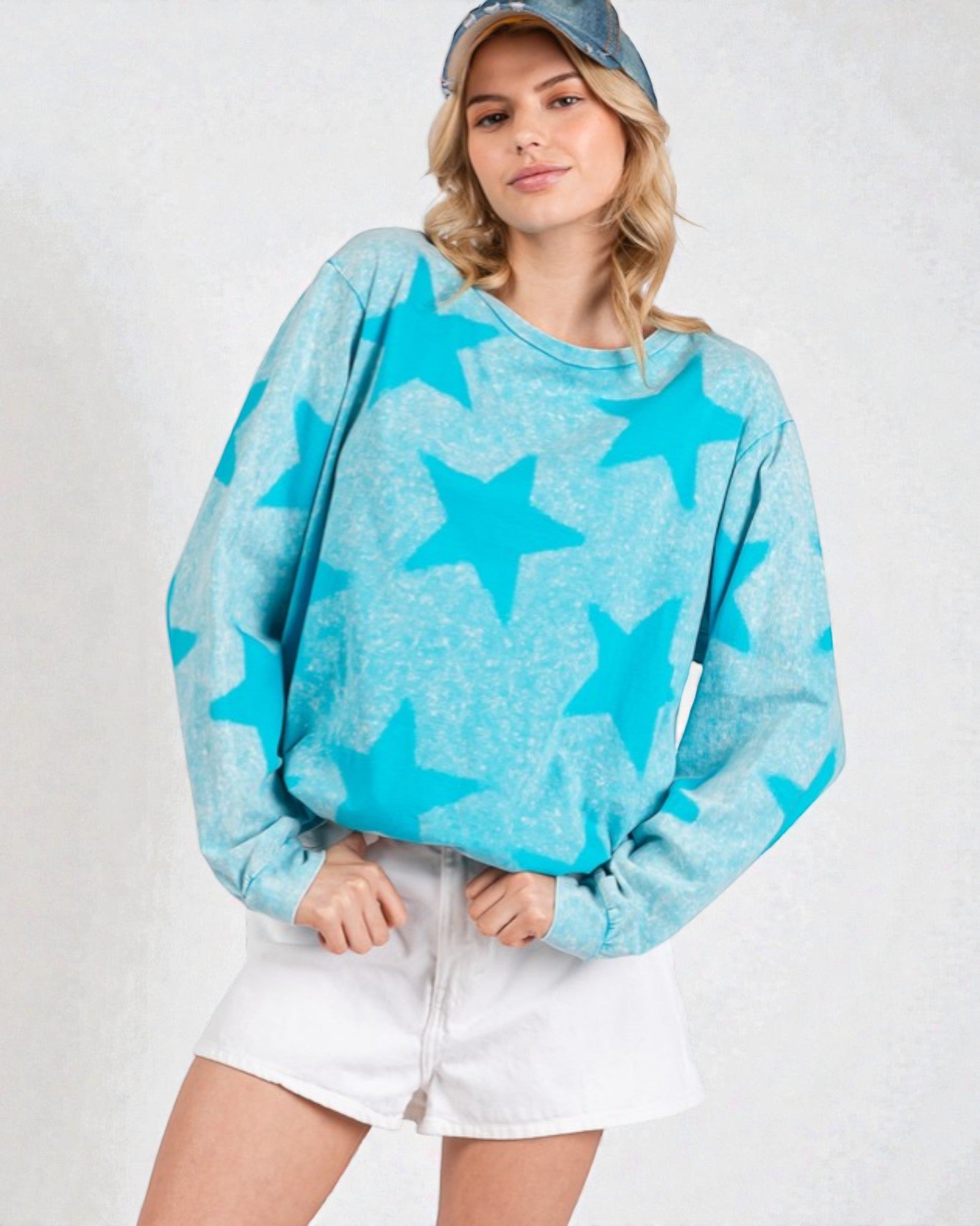 Person wearing a blue star-patterned sweater and white shorts on a plain background