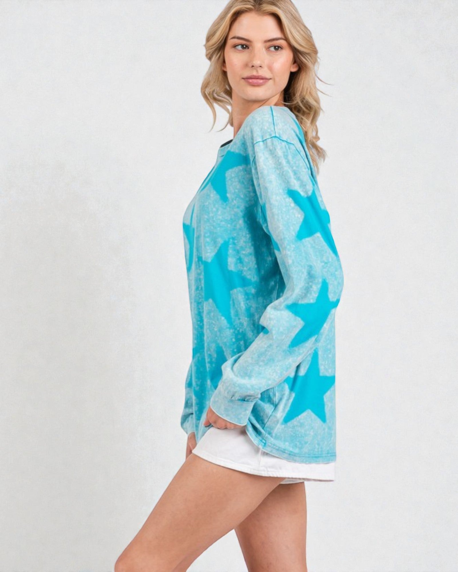 Woman wearing a turquoise star-patterned long-sleeve shirt on a white background
