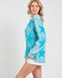 Woman wearing a turquoise star-patterned long-sleeve shirt on a white background