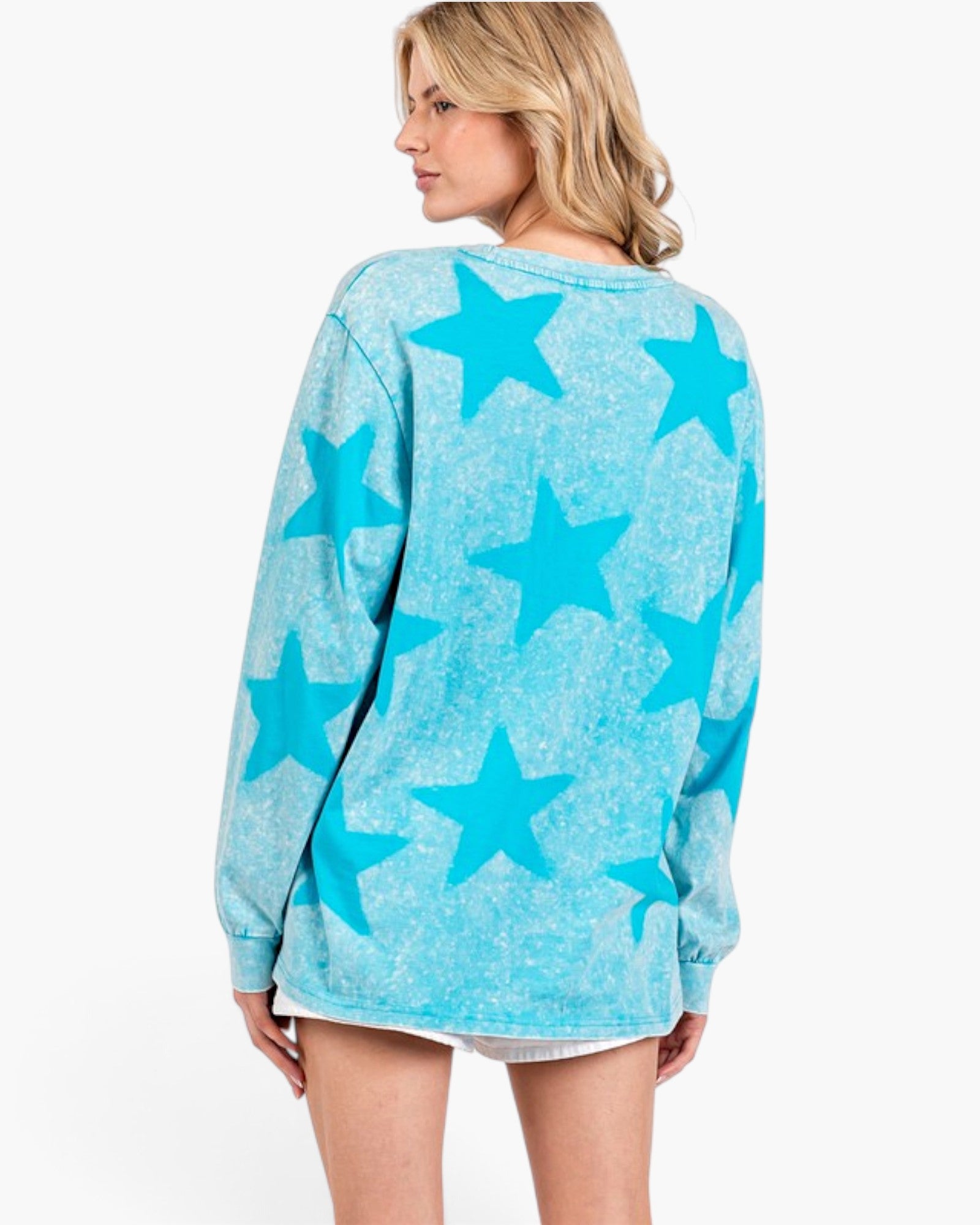A woman shown from the back wearing a light blue long-sleeve sweatshirt with a darker blue star pattern, set against a plain white studio background.