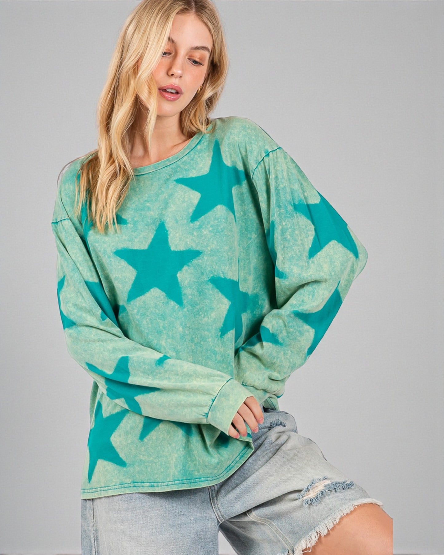 Woman wearing a green sweatshirt with star patterns on a gray background