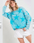 Woman wearing a blue star-patterned sweater and white shorts on a light gray background
