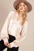 Woman wearing a beige satin blouse and brown hat against a neutral background