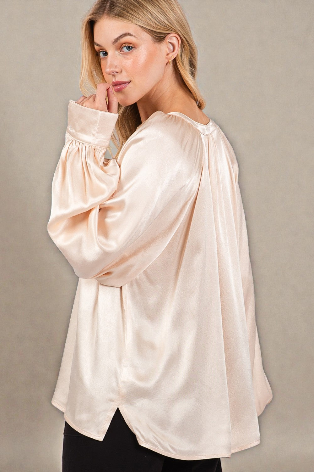Woman wearing a beige satin blouse against a neutral background