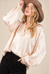 Woman wearing a beige satin blouse and brown hat against a neutral background