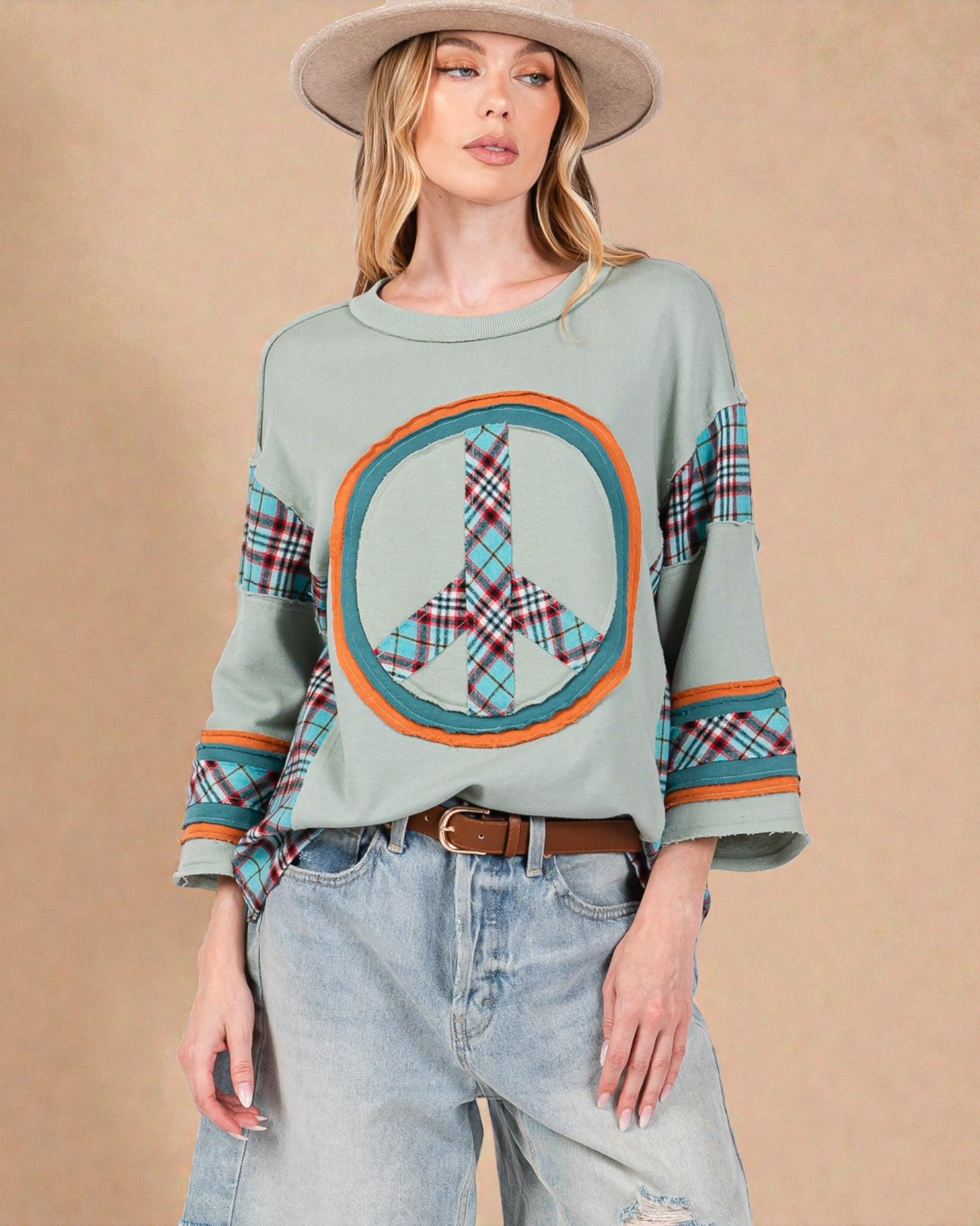 Woman wearing a light blue sweater with a peace symbol design on a beige background