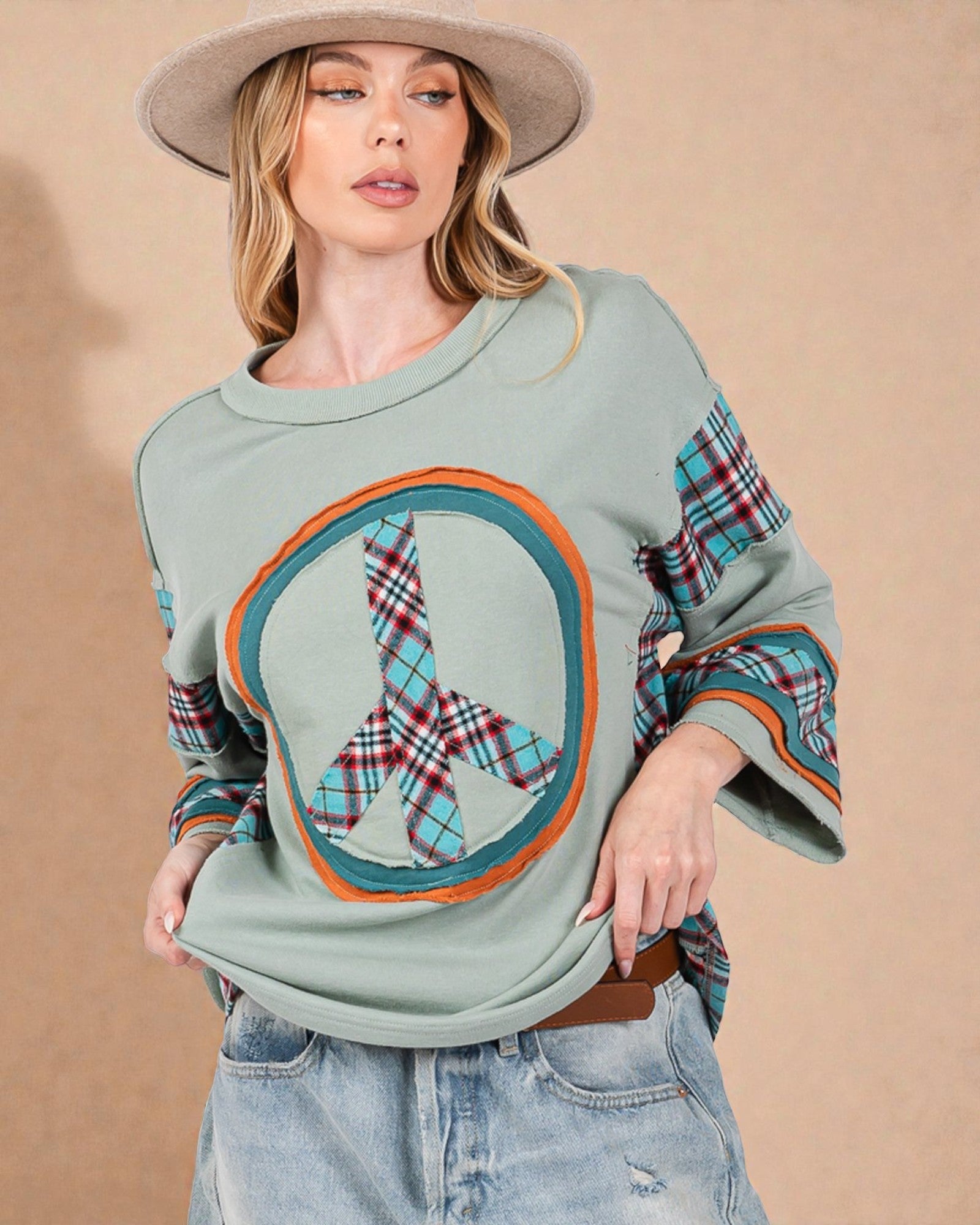 Woman wearing a light green sweater with plaid accents and a beige hat on a beige background