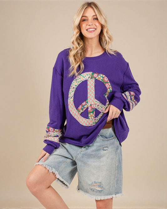 Woman wearing a purple sweatshirt with a peace symbol design on a beige background