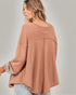 Woman wearing a brown oversized shirt with rolled-up sleeves on a gray background