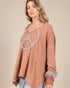 Woman wearing a brown sweater with a peace sign design on a beige background