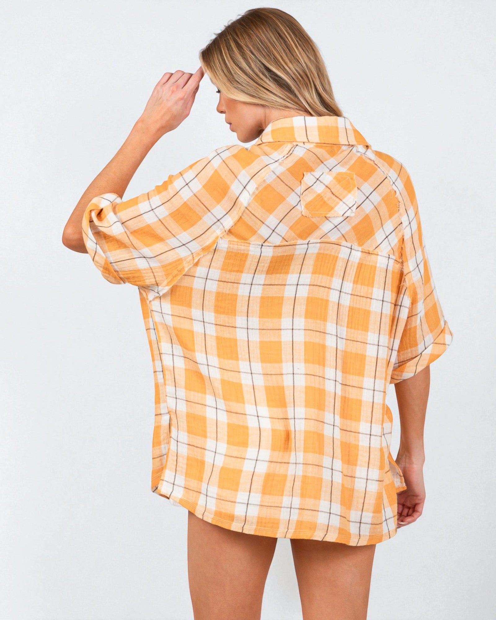 Woman wearing a yellow and white plaid shirt against a plain background