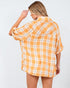 Woman wearing a yellow and white plaid shirt against a plain background
