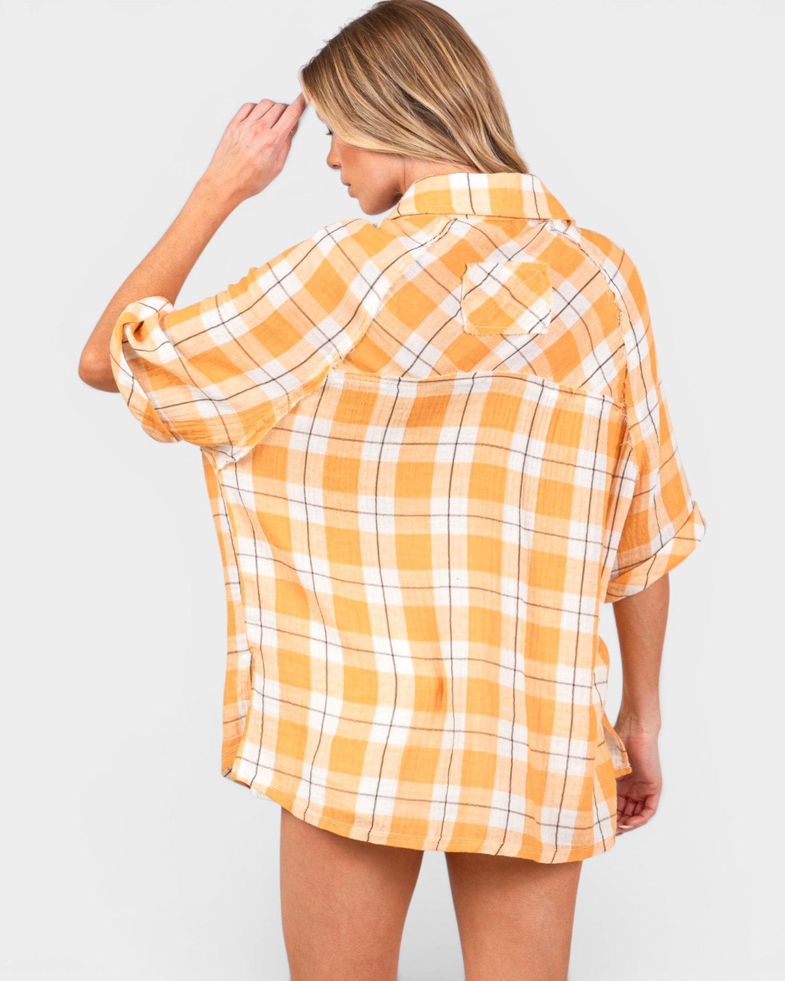 Woman wearing a yellow and white plaid shirt on a plain background