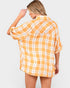 Woman wearing a yellow and white plaid shirt on a plain background