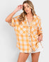 Woman wearing a yellow plaid shirt and white shorts on a light gray background
