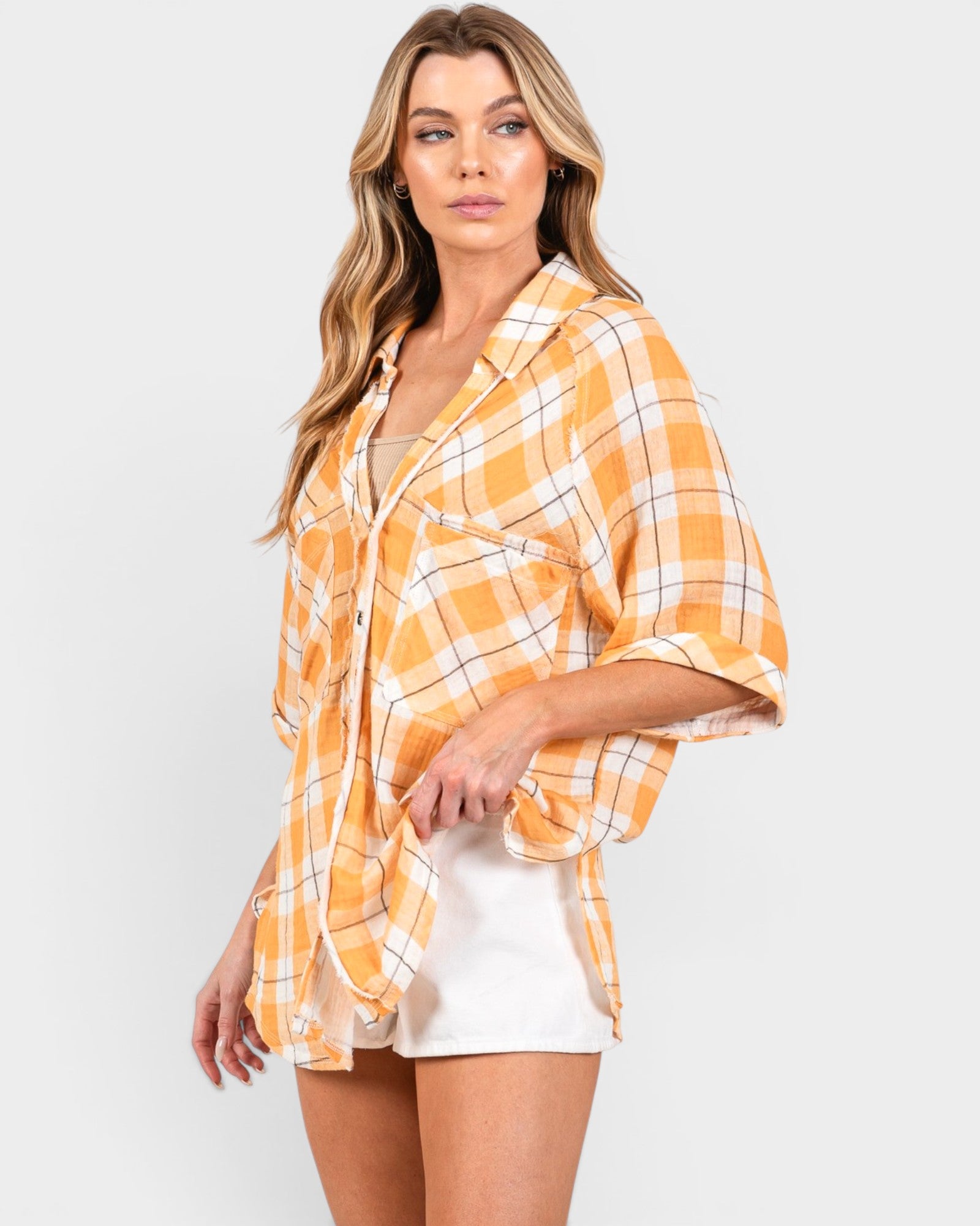Woman wearing a yellow plaid shirt over a white dress on a white background