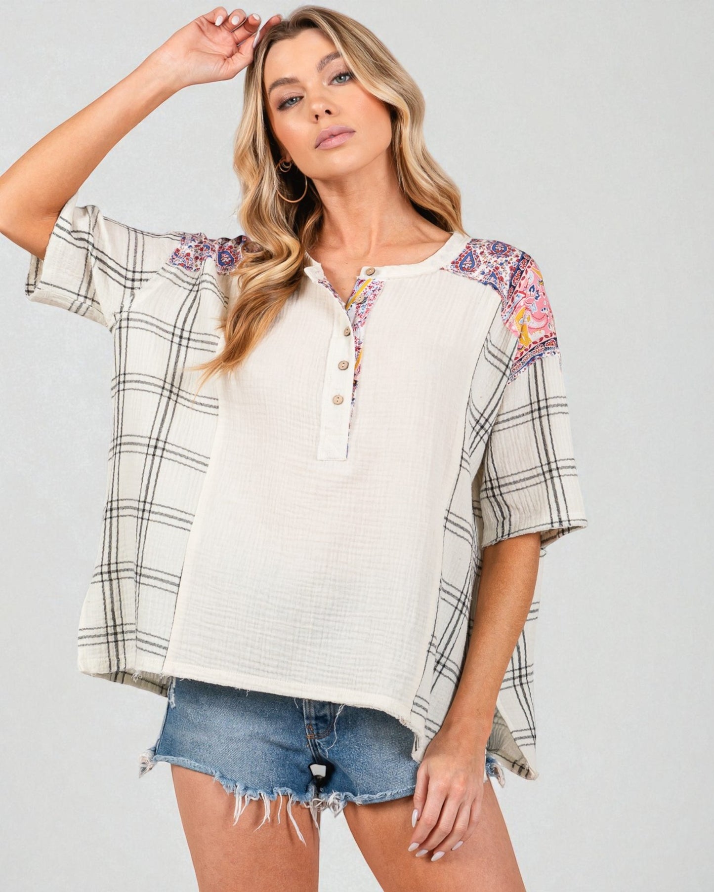 Woman wearing a plaid shirt with floral sleeves on a plain background