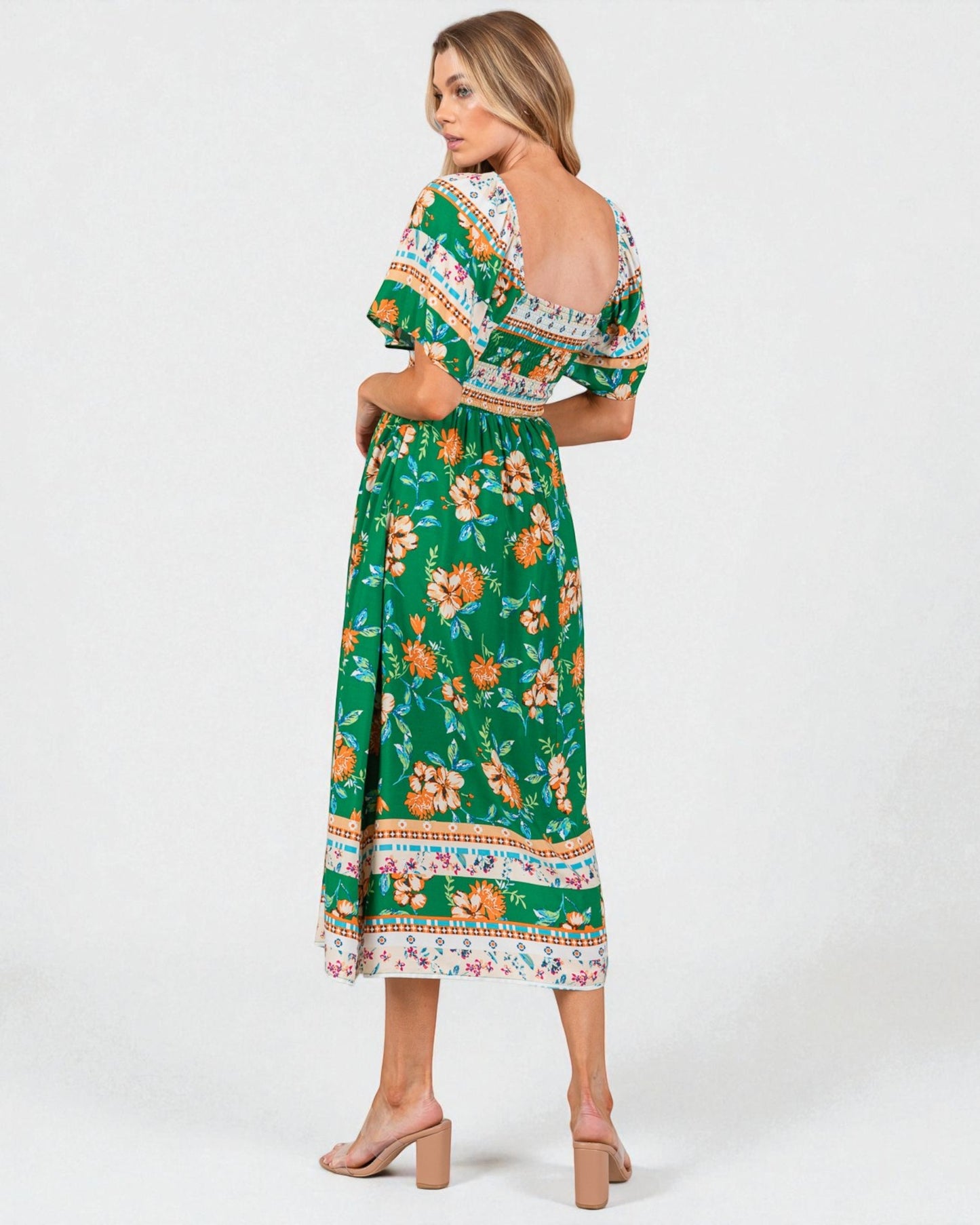 Woman wearing a green floral dress with a white background