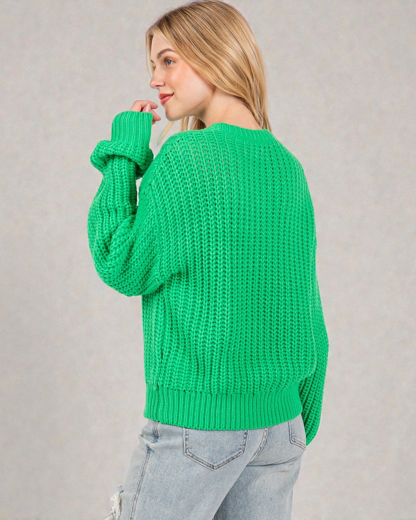 Person wearing a green sweater against a plain background