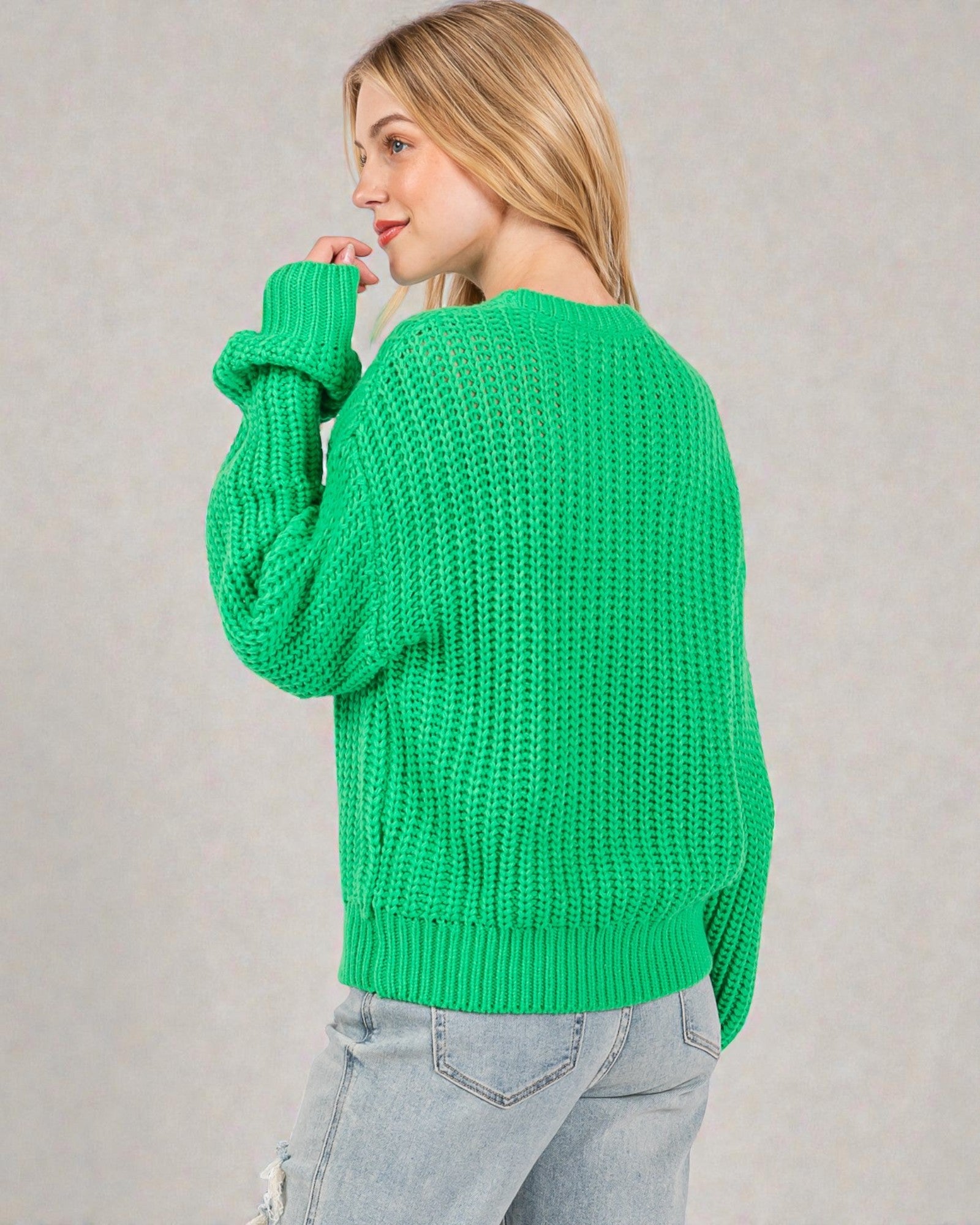Person wearing a green sweater against a plain background