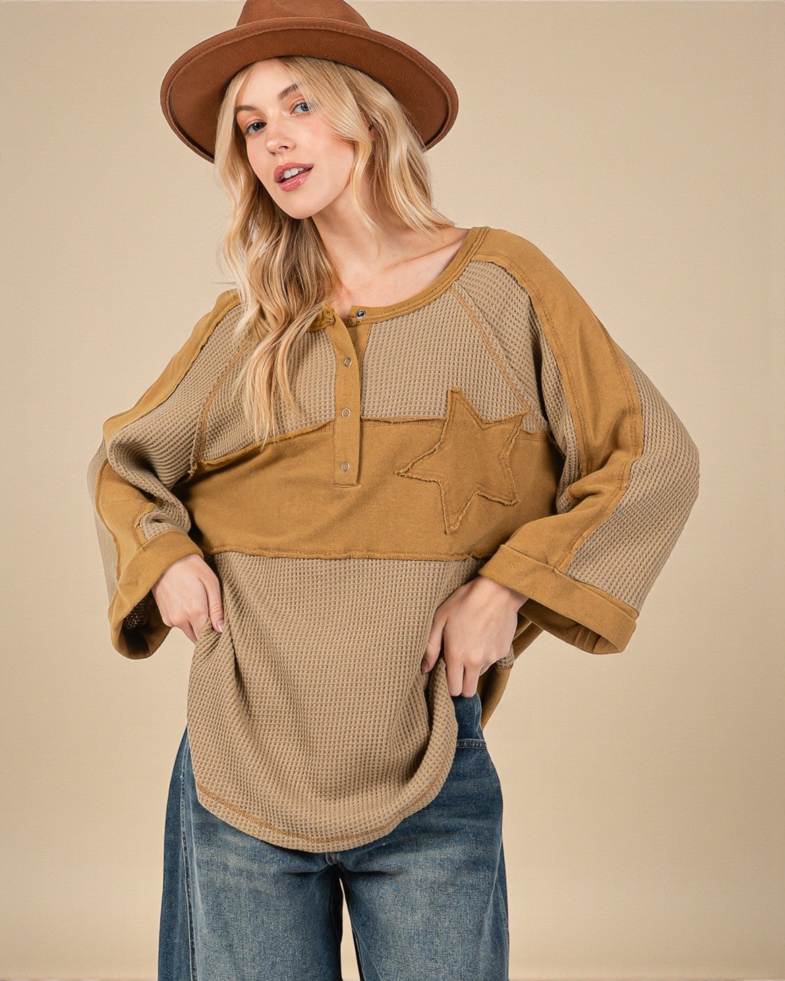 Woman wearing a brown and beige layered top with a star detail on a beige background